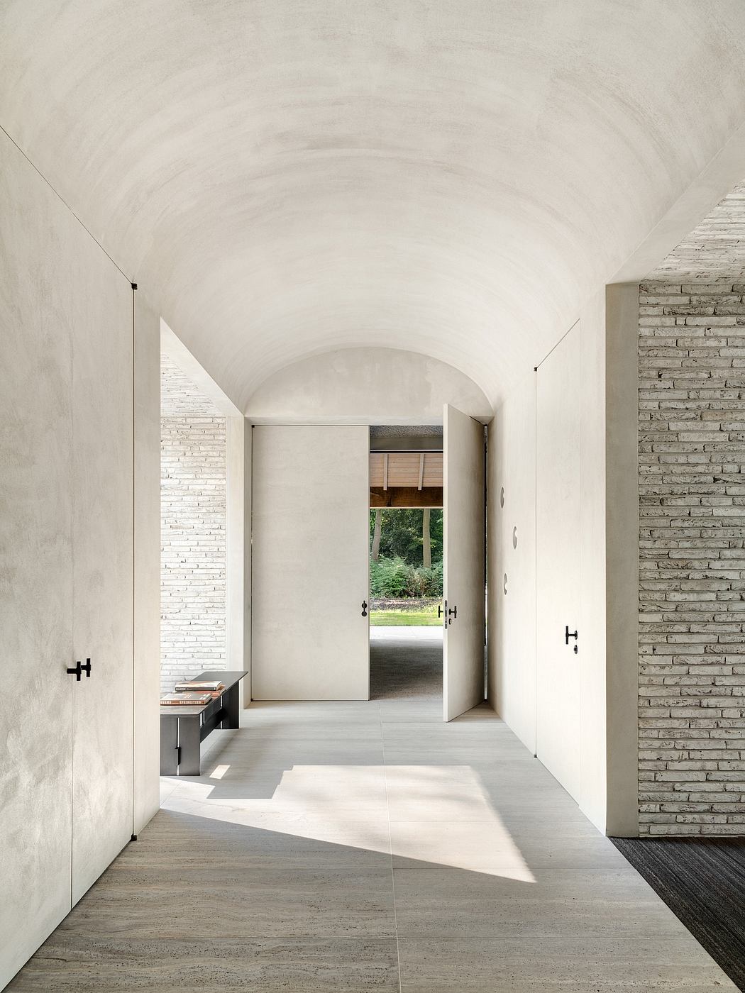 Minimalist architectural interior with arched ceiling, natural materials, and outdoor view.