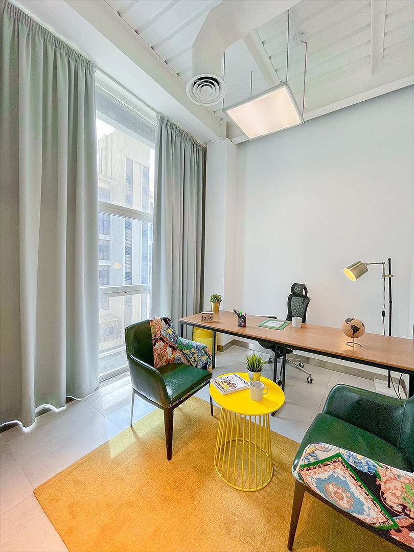 Vibrant workspace with modern furniture, large window, and bright lighting elements.