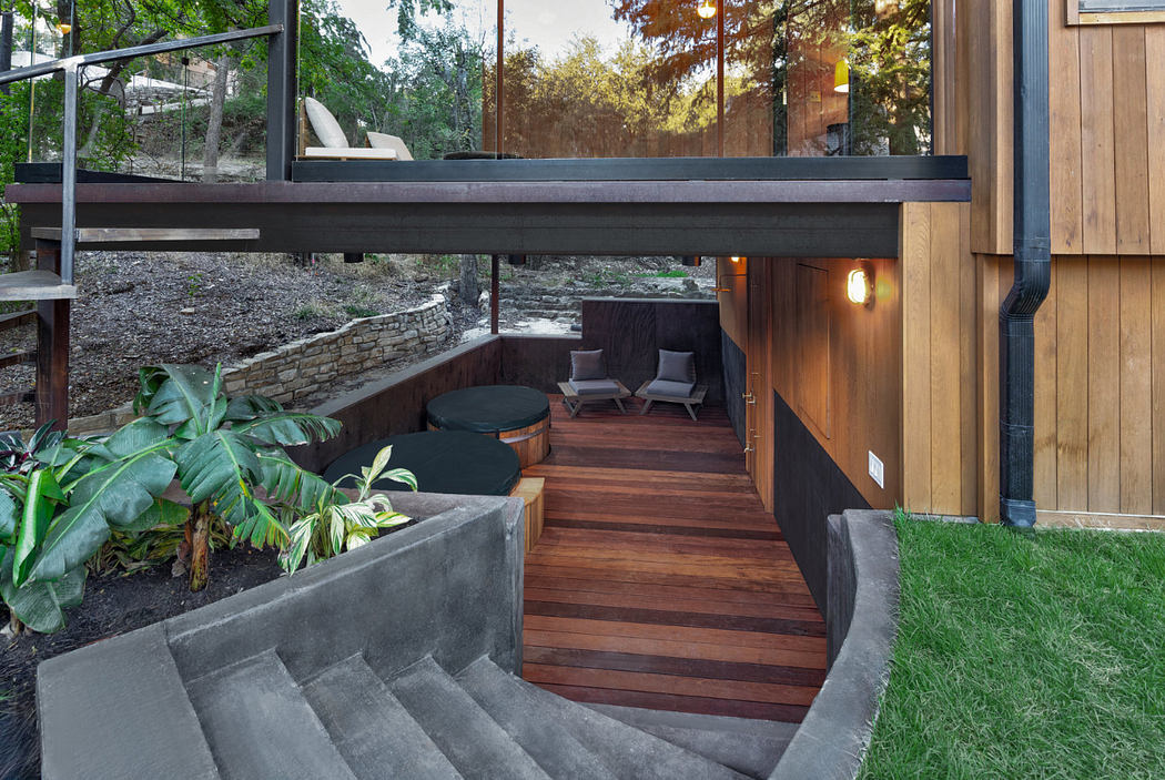 Wooden deck, concrete stairs, and lush greenery create a serene outdoor space.