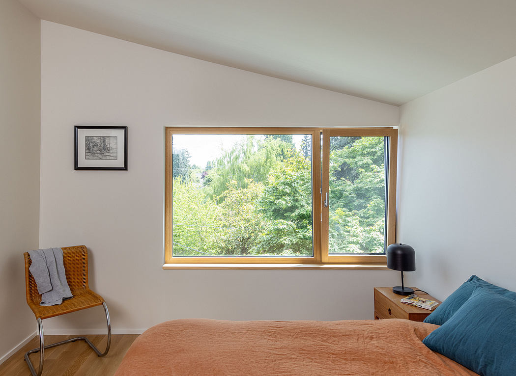 Warm, minimalist room with large wooden-framed window overlooking lush greenery.