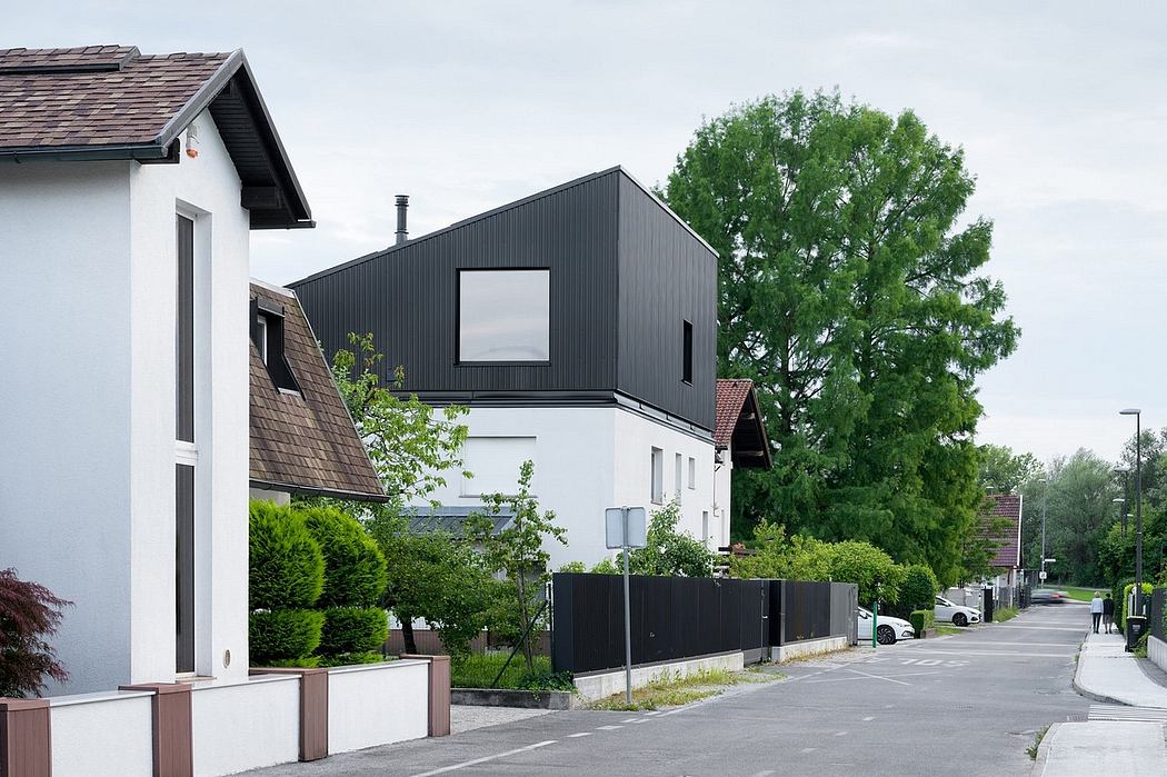 Modern architectural details of a white and black residential home with a slanted roof and large windows, surrounded by lush greenery.