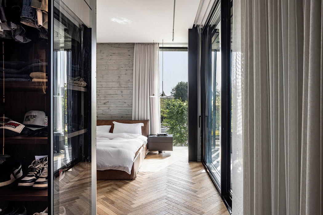 Modern bedroom with concrete walls, herringbone wood floors, and floor-to-ceiling windows.