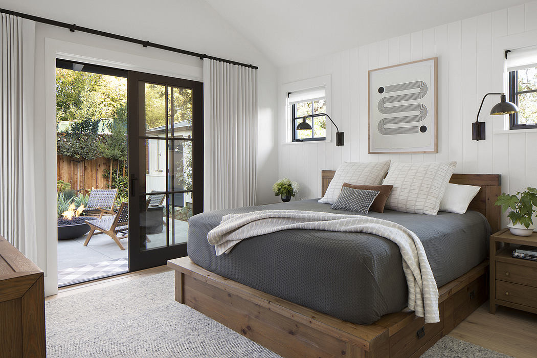 Spacious bedroom with wooden platform bed, gray linens, and framed artwork on white walls.