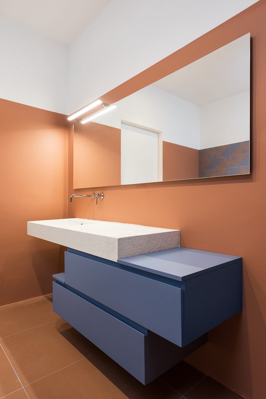 Sleek modern bathroom with white sink, navy blue vanity, and warm-toned wall panels.