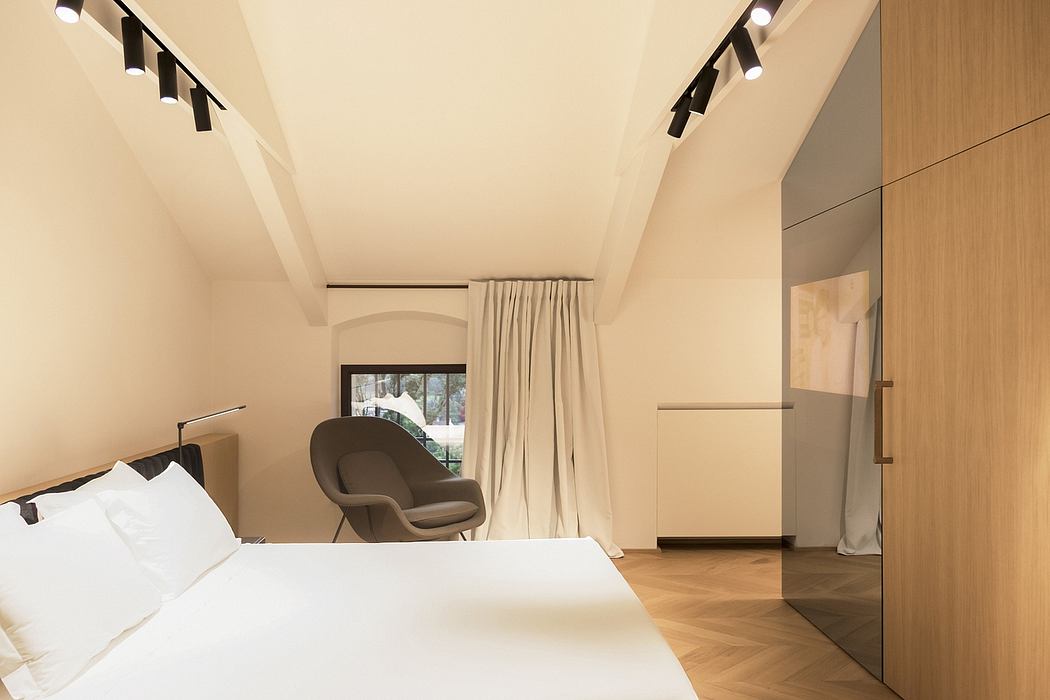 Well-designed modern bedroom with arched window, neutral tones, and track lighting.