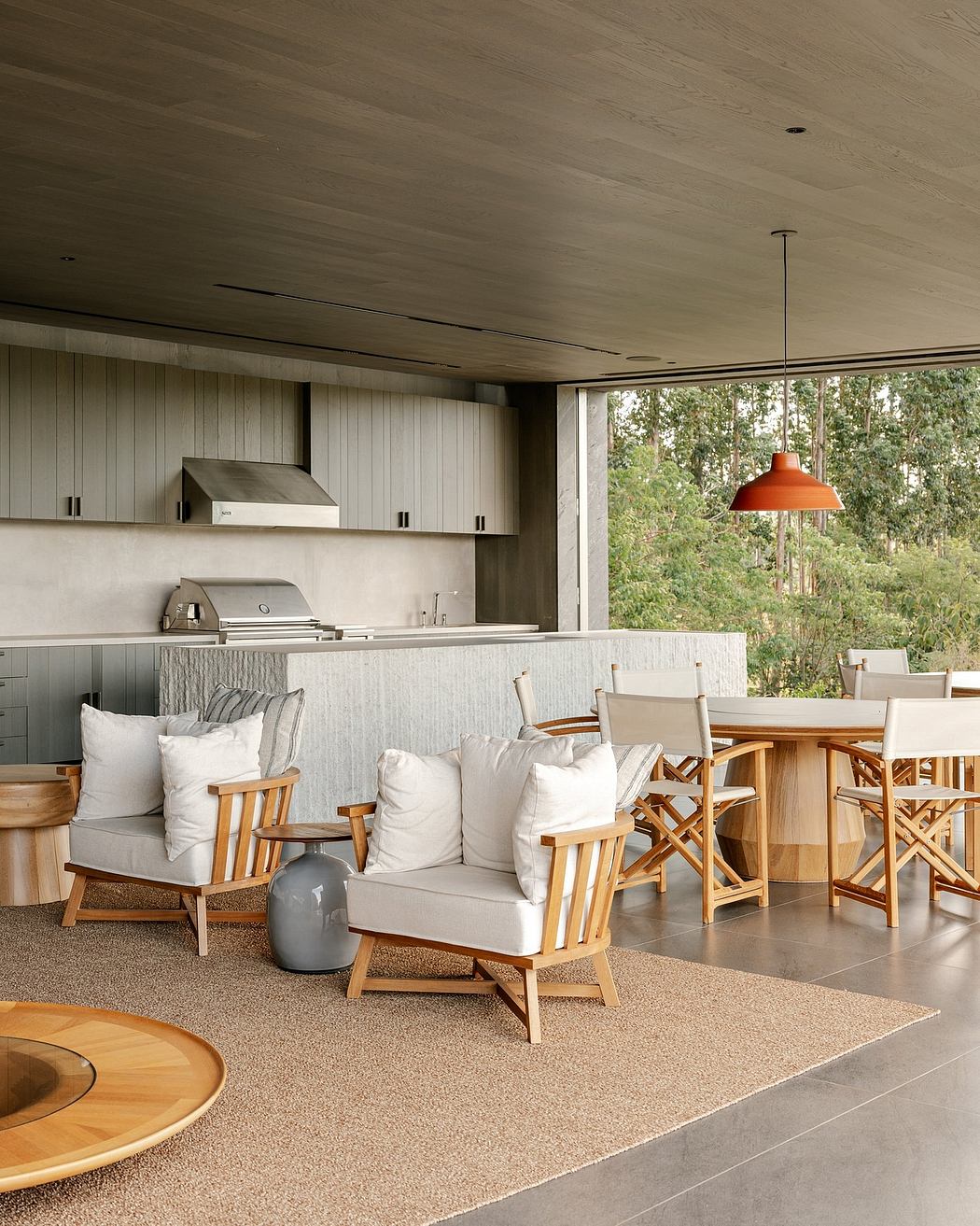 A modern, open-concept kitchen and living space with natural wood furnishings, a large window, and an inviting outdoor view.