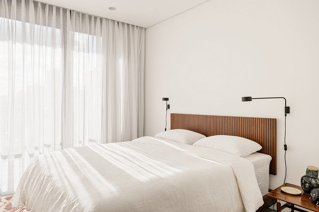 Contemporary bedroom with wooden headboard, minimal decor, and floor-to-ceiling curtains for privacy.