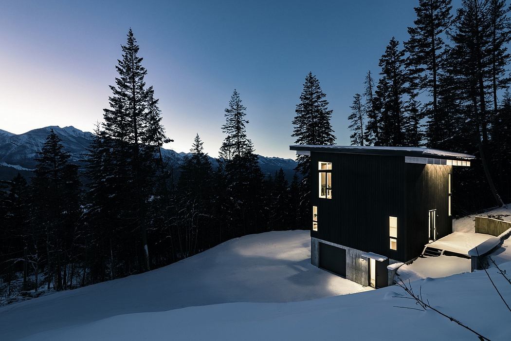 A modern cabin nestled in a snowy, forested landscape surrounded by majestic mountains.