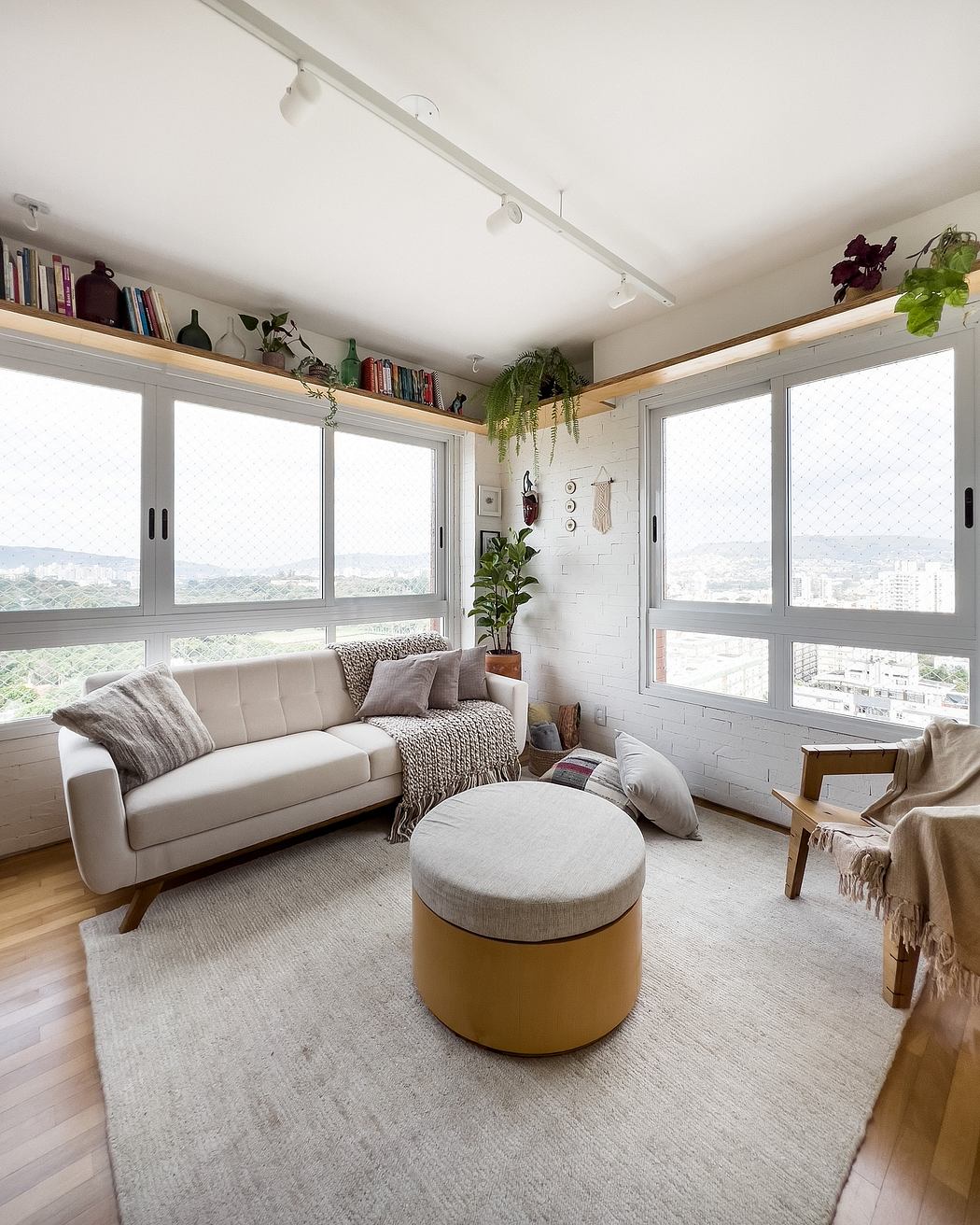 Minimalist living room with soothing gray palette, shelves, and large windows offering city views.
