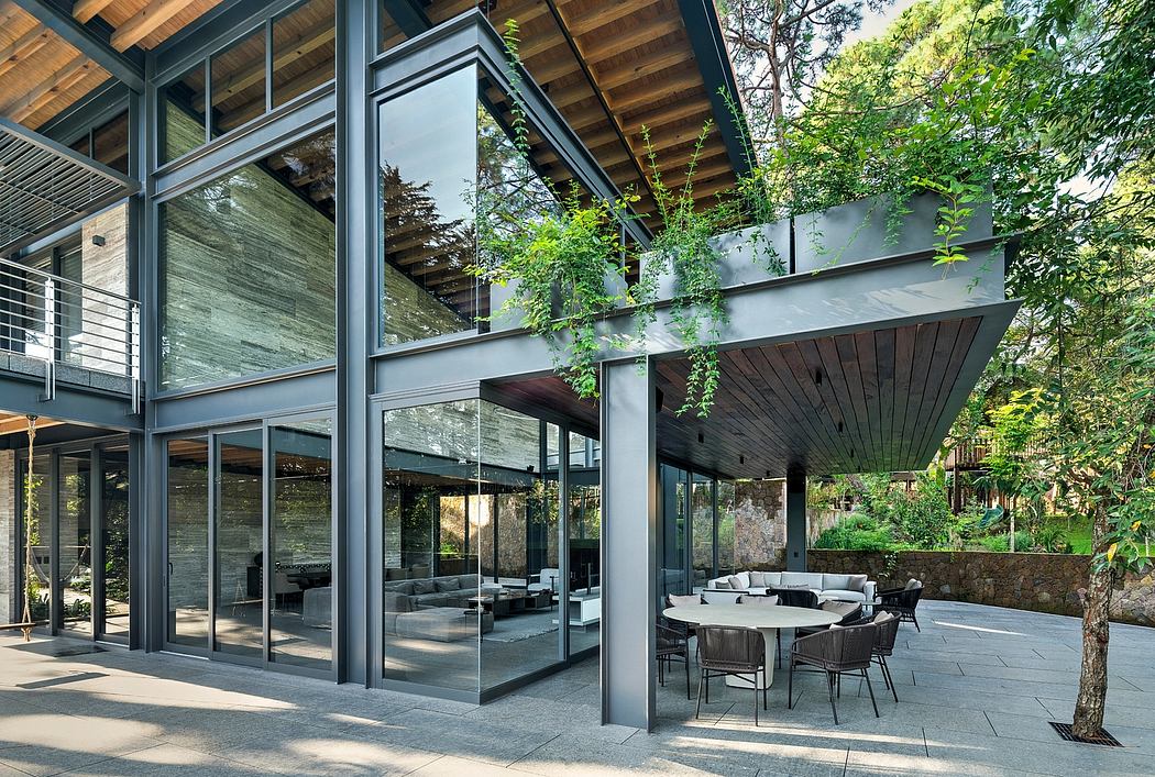 Modern glass and wood exterior with cantilevered roof, surrounding patio, and lush greenery.
