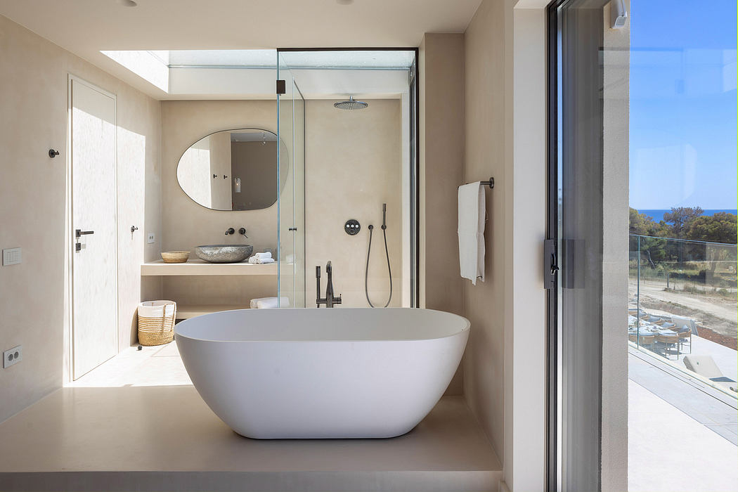 Spacious, modern bathroom with freestanding bathtub, glass shower, and panoramic ocean views.