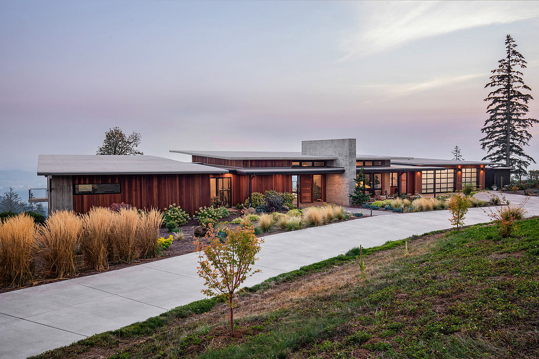 Modern wood-and-concrete home with slanted roofs, grassy landscaping, and large windows.