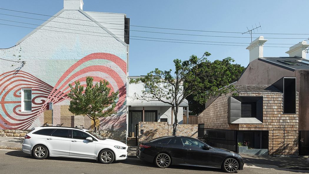 Vibrant mural adorns the exterior of a modern residential building with cars parked.