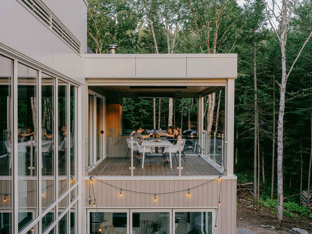 Inviting outdoor deck with covered seating area and string lighting, nestled in a lush forest.