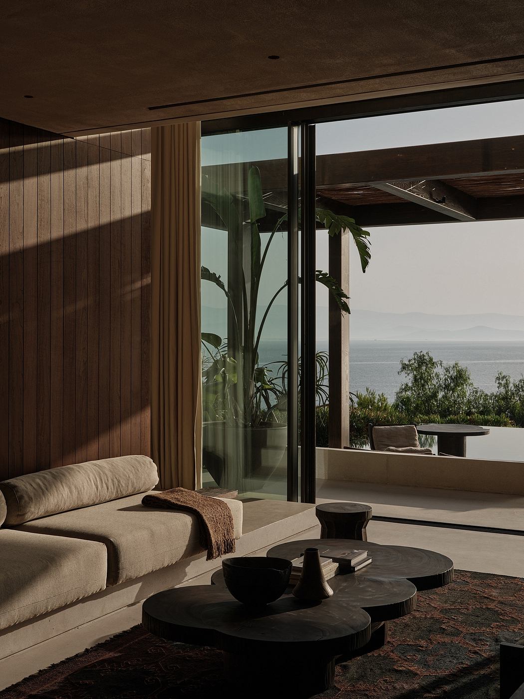 Serene interior with panoramic ocean view, wood panels, and minimalist furniture.