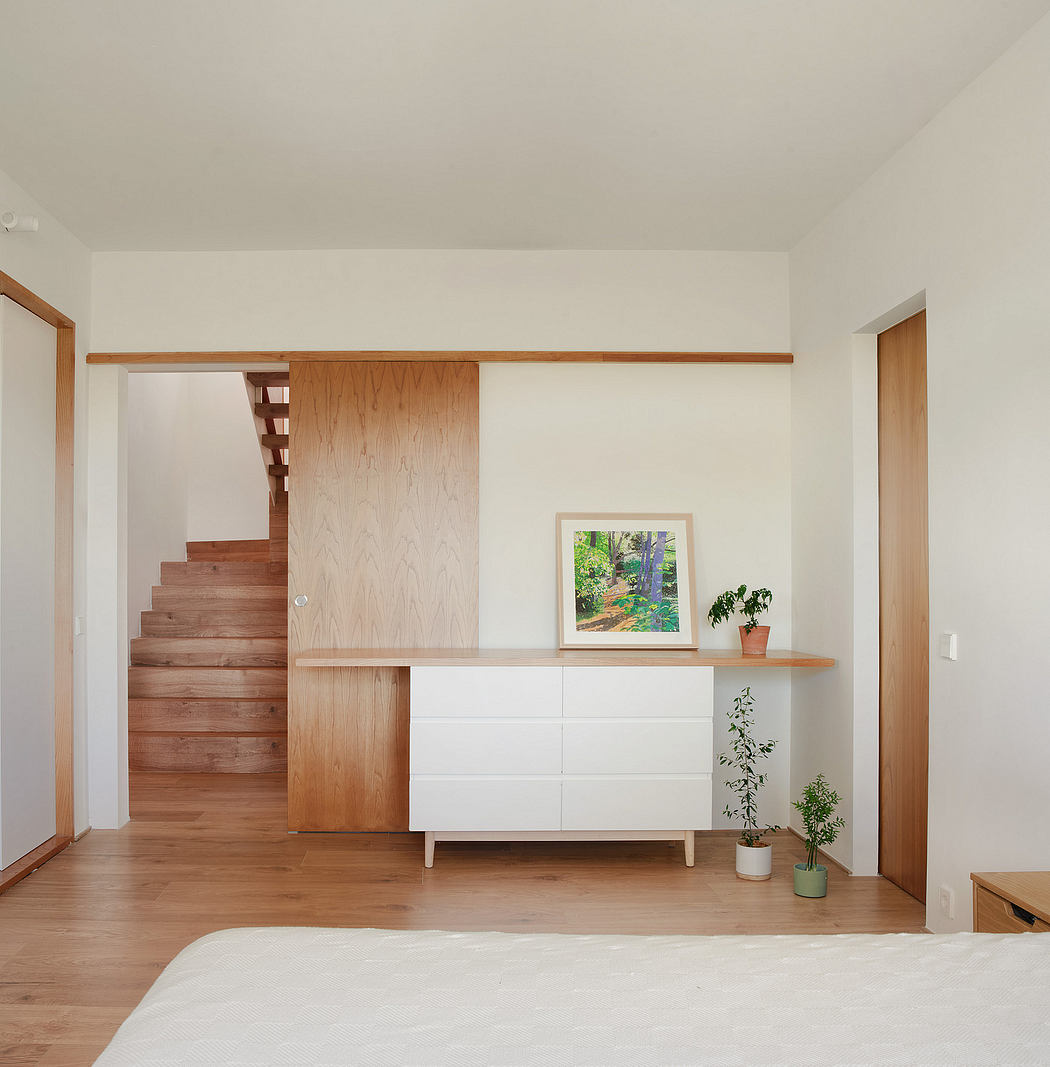 Minimalist interior with wood stairs, built-in shelves, and decorative potted plants.