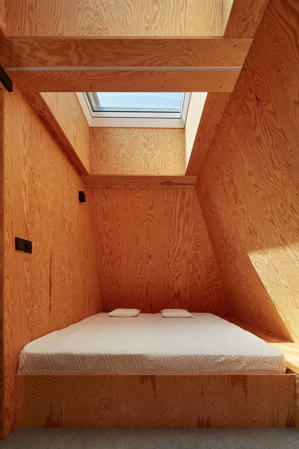 A cozy wood-paneled bedroom with a skylight, minimalist design, and a simple bed.