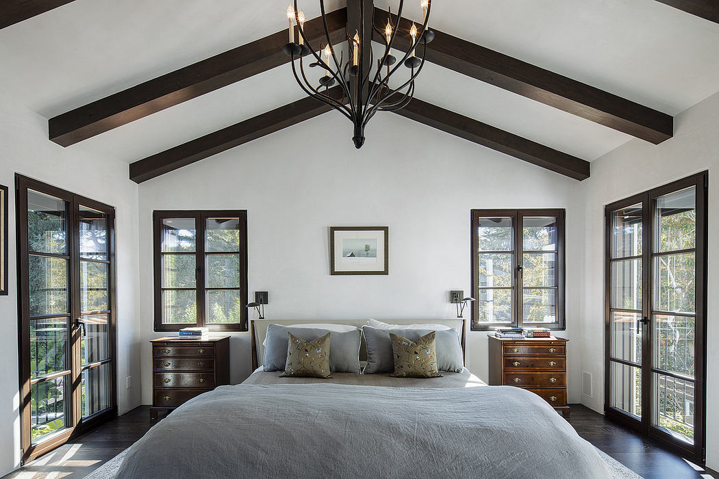 Spacious bedroom with vaulted ceiling, dark wood beams, and decorative light fixture.