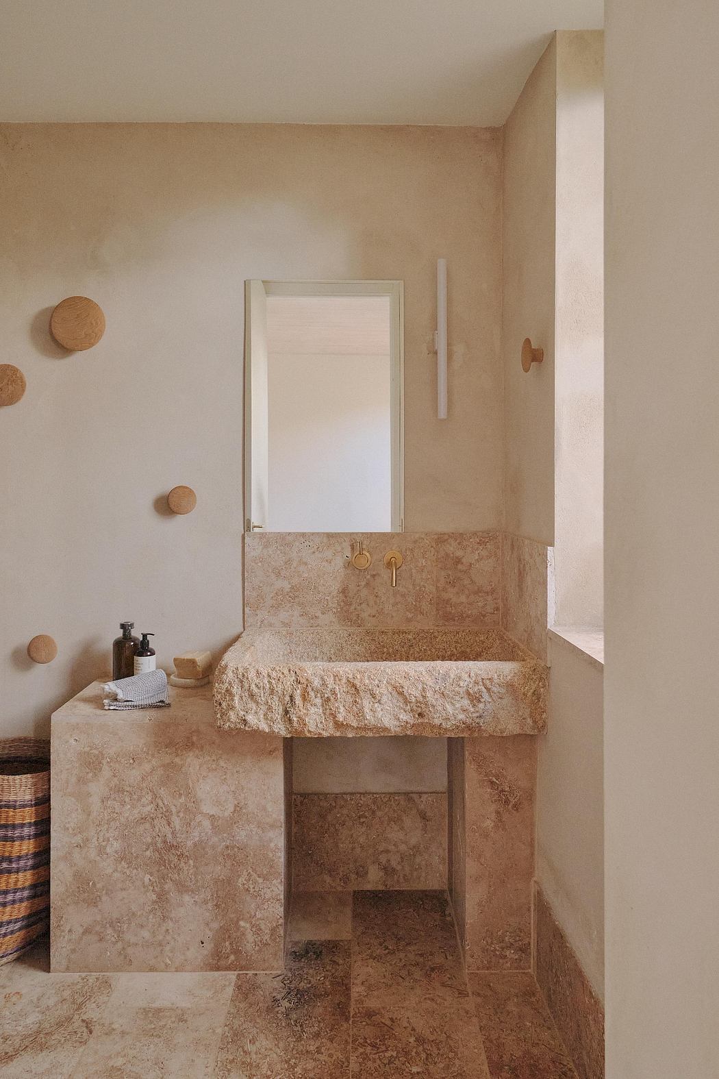 A minimalist bathroom with a rustic stone vanity, mirror, and wooden accents.