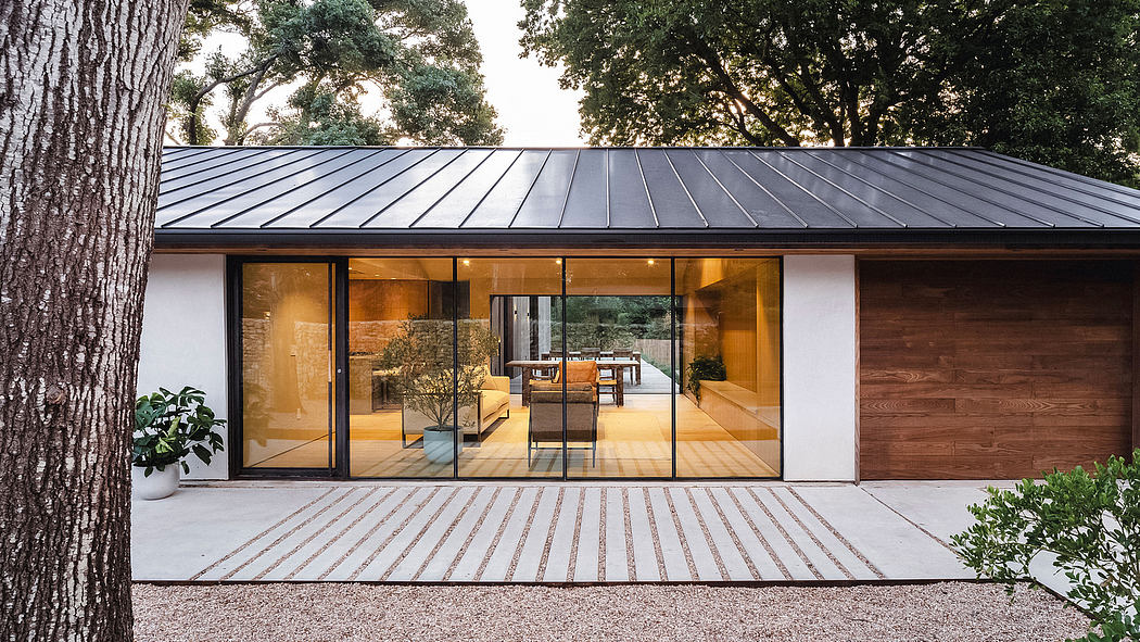 Modern, open-plan home with large glass walls, sleek metal roof, and wooden accents blending seamlessly with nature.