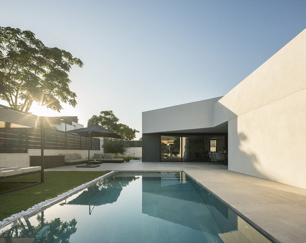A modern, minimalist home with a pool reflecting the surrounding trees and sky.
