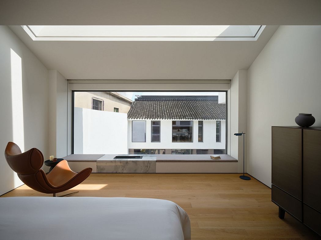 Minimalist bedroom with marble-topped platform bed, wood floors, and curved armchair.