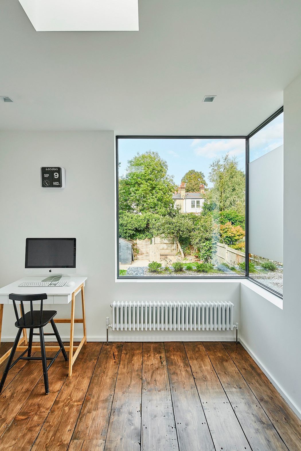 Modern minimalist home office with expansive window overlooking lush outdoor scenery.