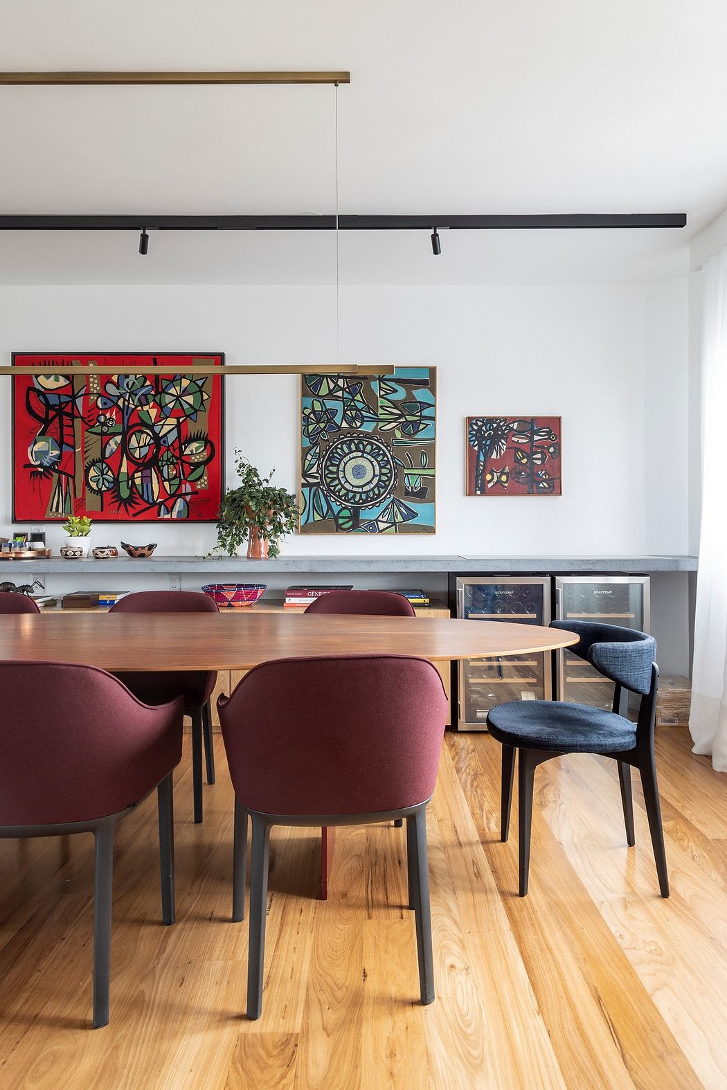 A modern dining area with a wooden table, colorful abstract art, and built-in shelving.