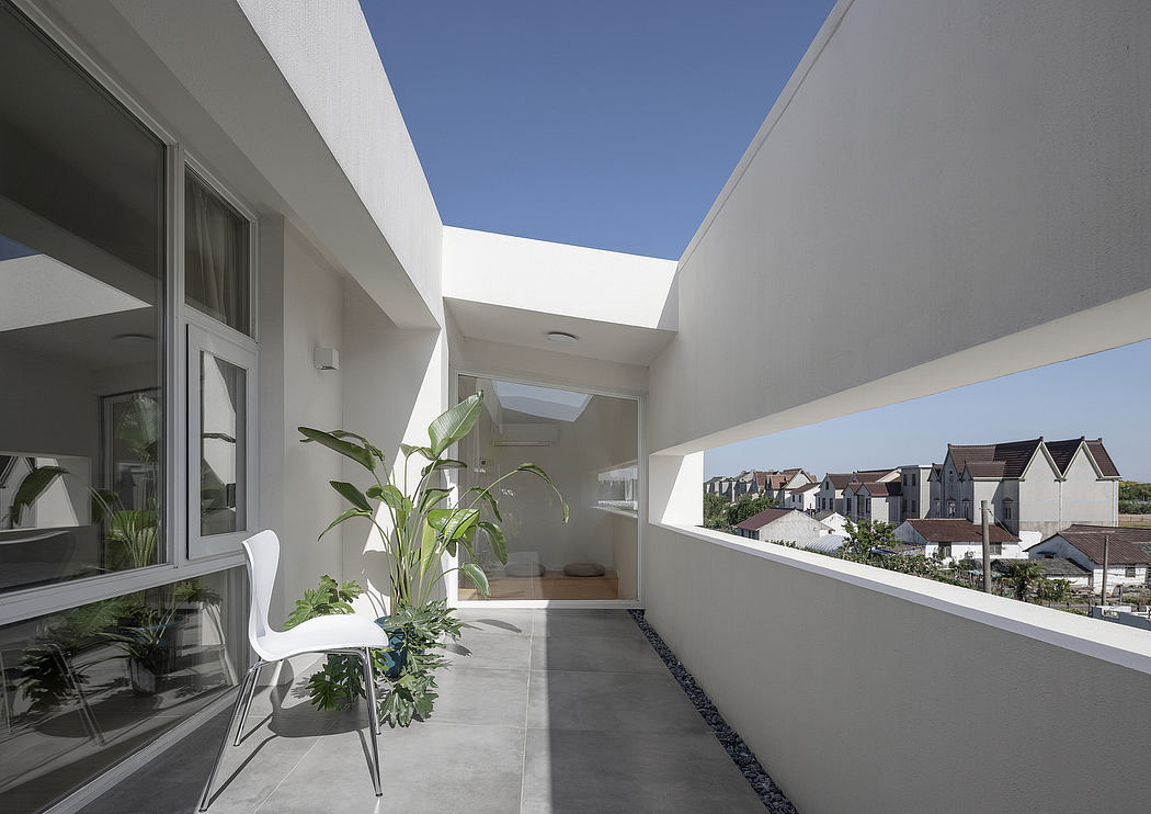 Sleek, modern balcony with minimalist white furniture, lush greenery, and expansive skylight.