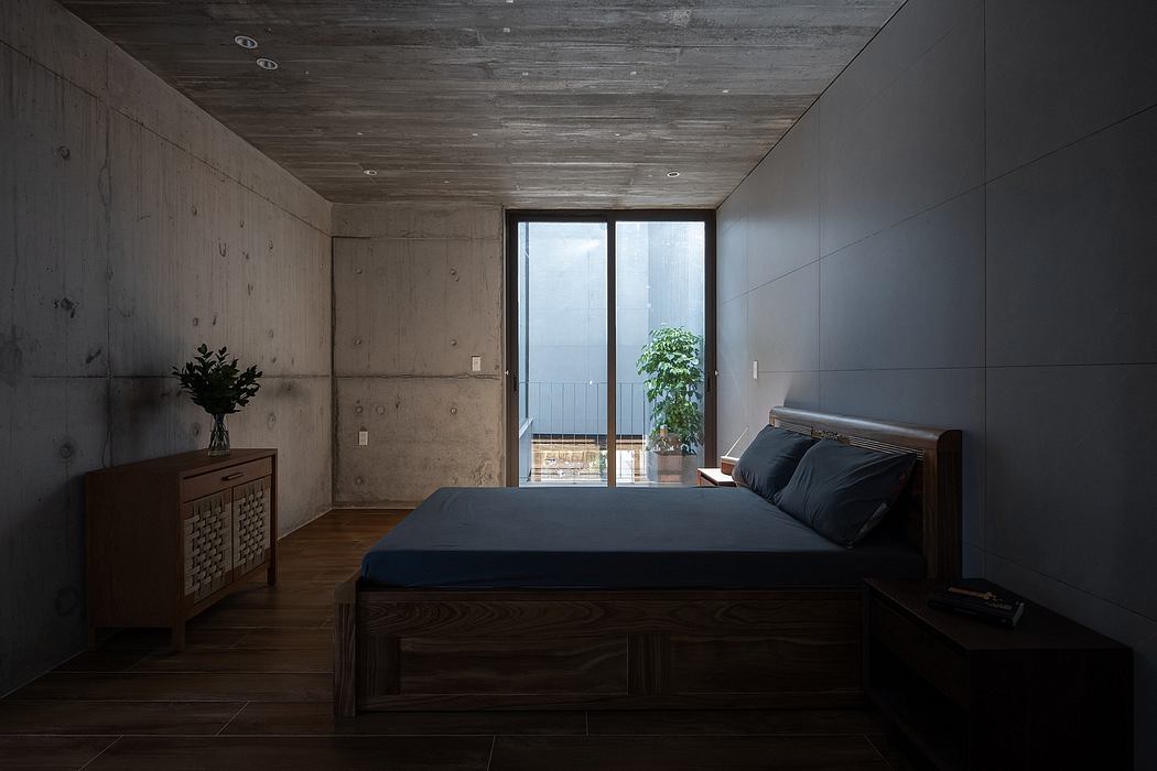 Minimalist bedroom with concrete walls, wooden ceiling, and sleek black furnishings.