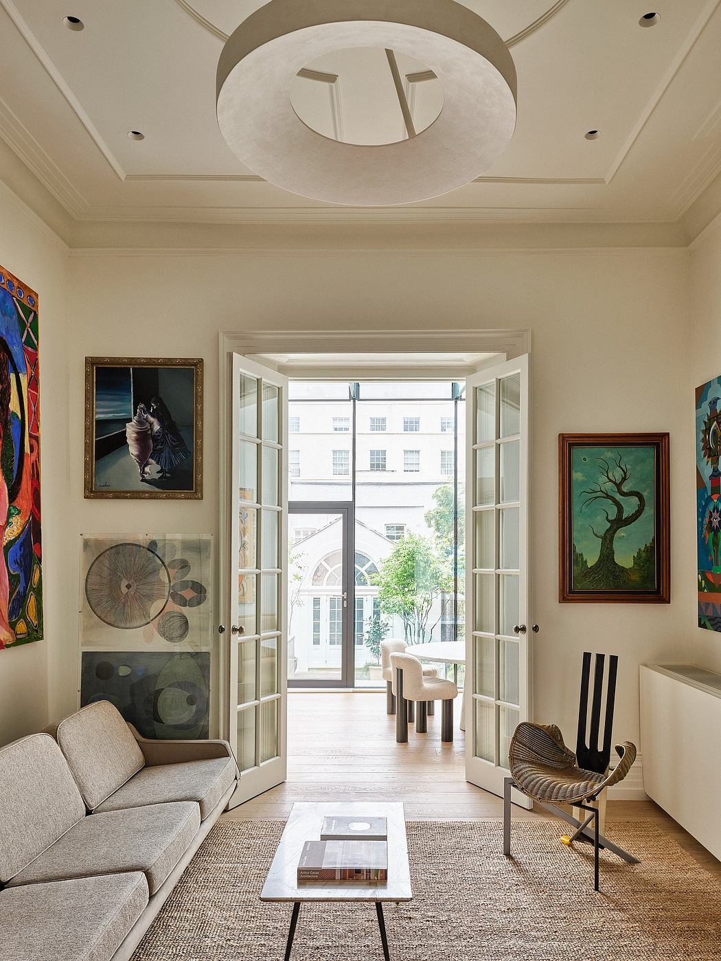Elegant living room with ornate ceiling, French doors, and eclectic artwork displays.