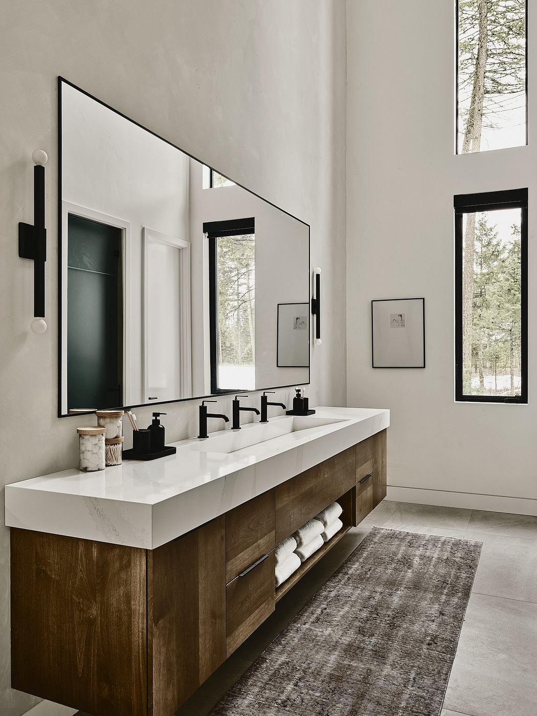 A modern bathroom with a double vanity, black fittings, and a large mirror framed in black.