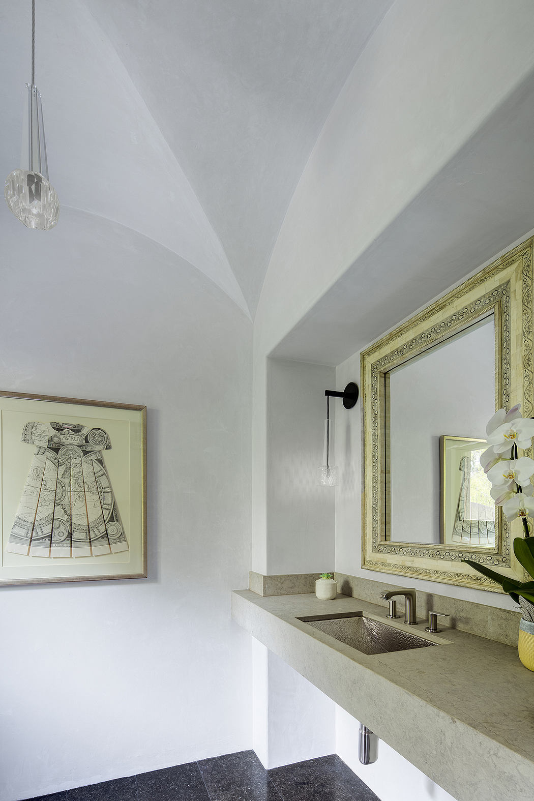 A modern yet ornate bathroom with decorative framed artwork, vanity, and lighting fixture.