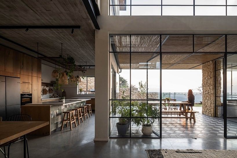 Spacious, open-concept kitchen with rustic wooden beams, floor-to-ceiling windows, and a balcony overlooking scenic views.