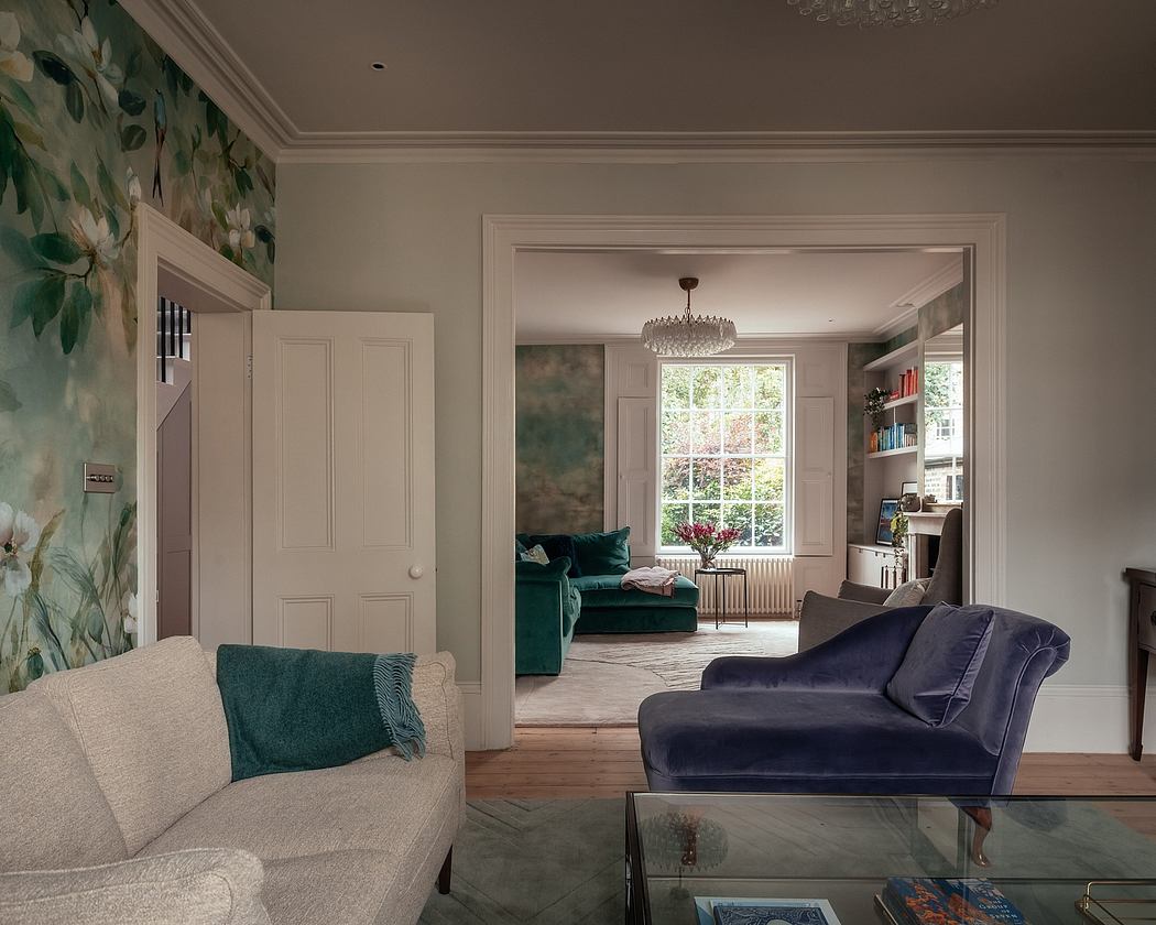 A cozy living room with floral wallpaper, plush furniture, and a chandelier overhead.