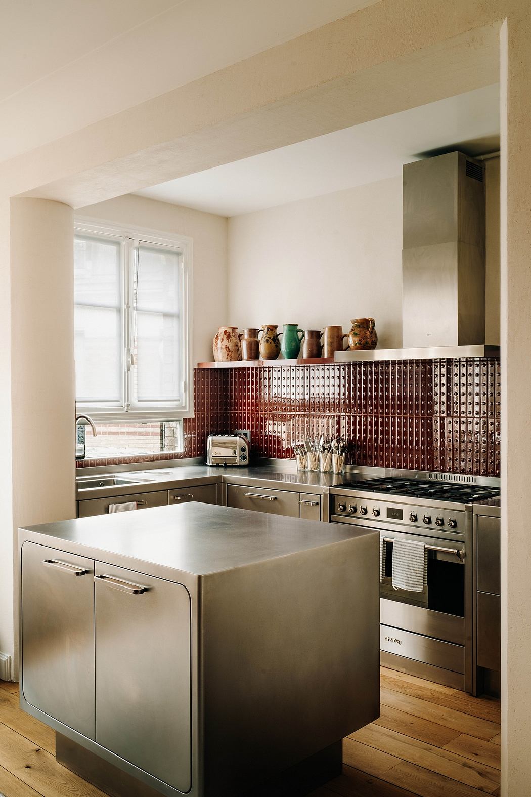 Spacious kitchen with stainless steel appliances, terracotta backsplash, and hardwood floors.