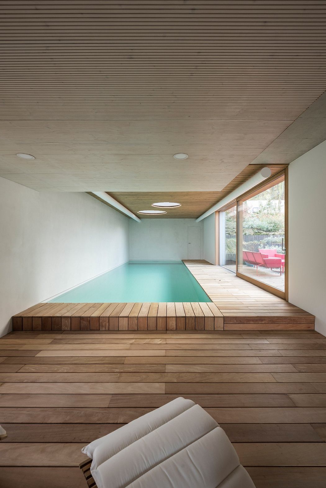 A modern interior with a wooden platform, a swimming pool, and a comfortable seating area.