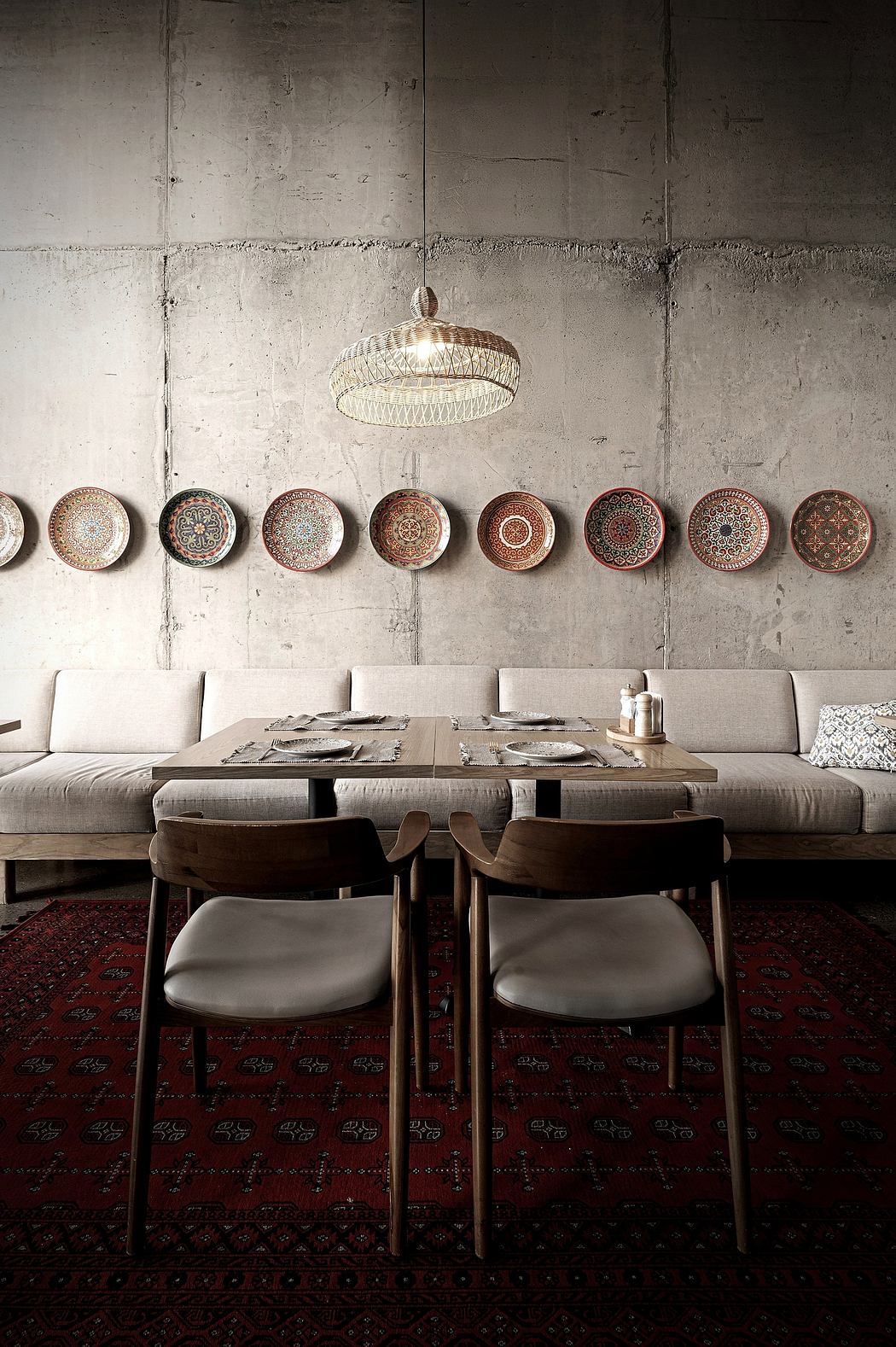 A rustic dining area with a woven pendant light, ornate wall plates, and textured seating.