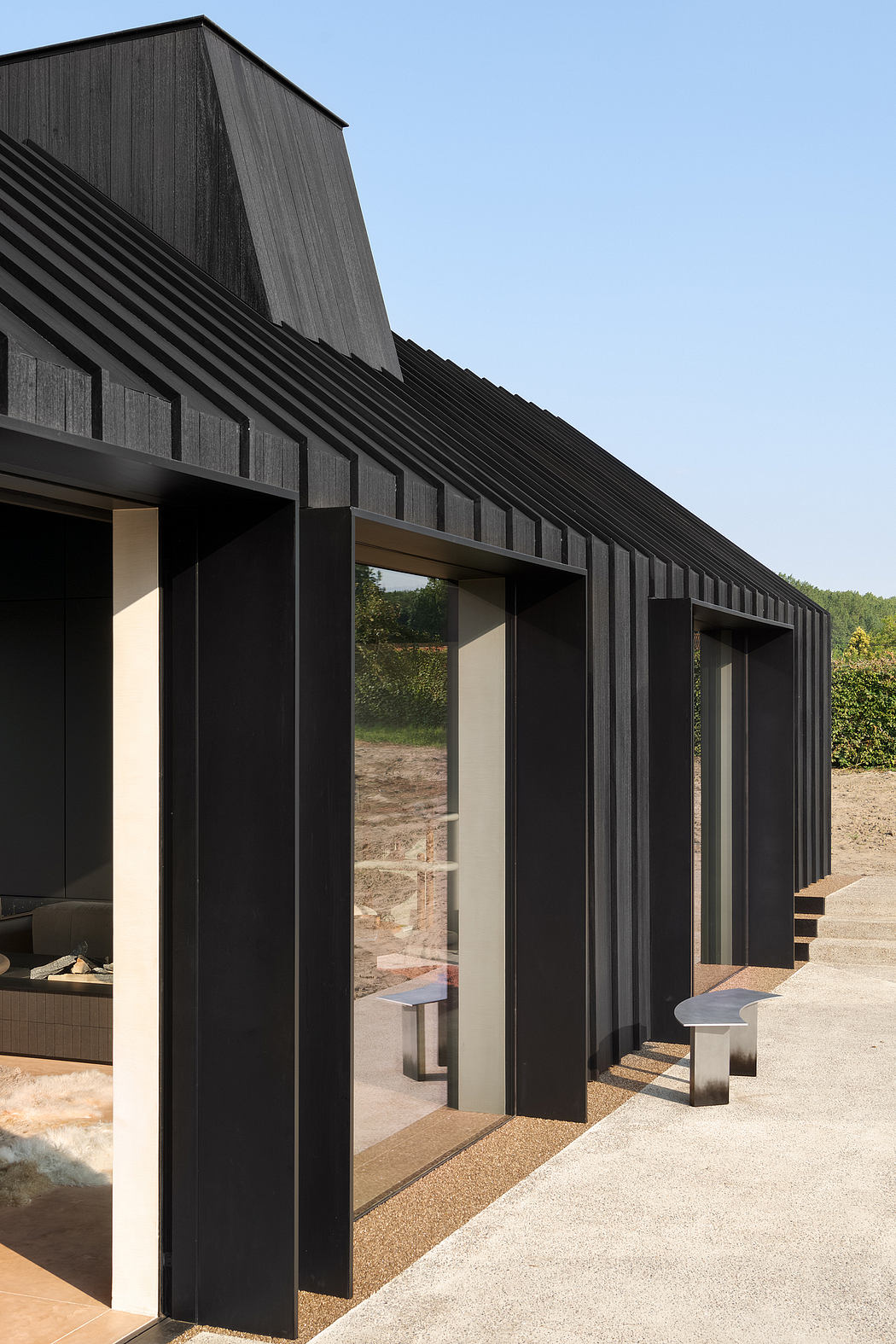A modern, black-clad building with striking angled rooflines and expansive glass panels.
