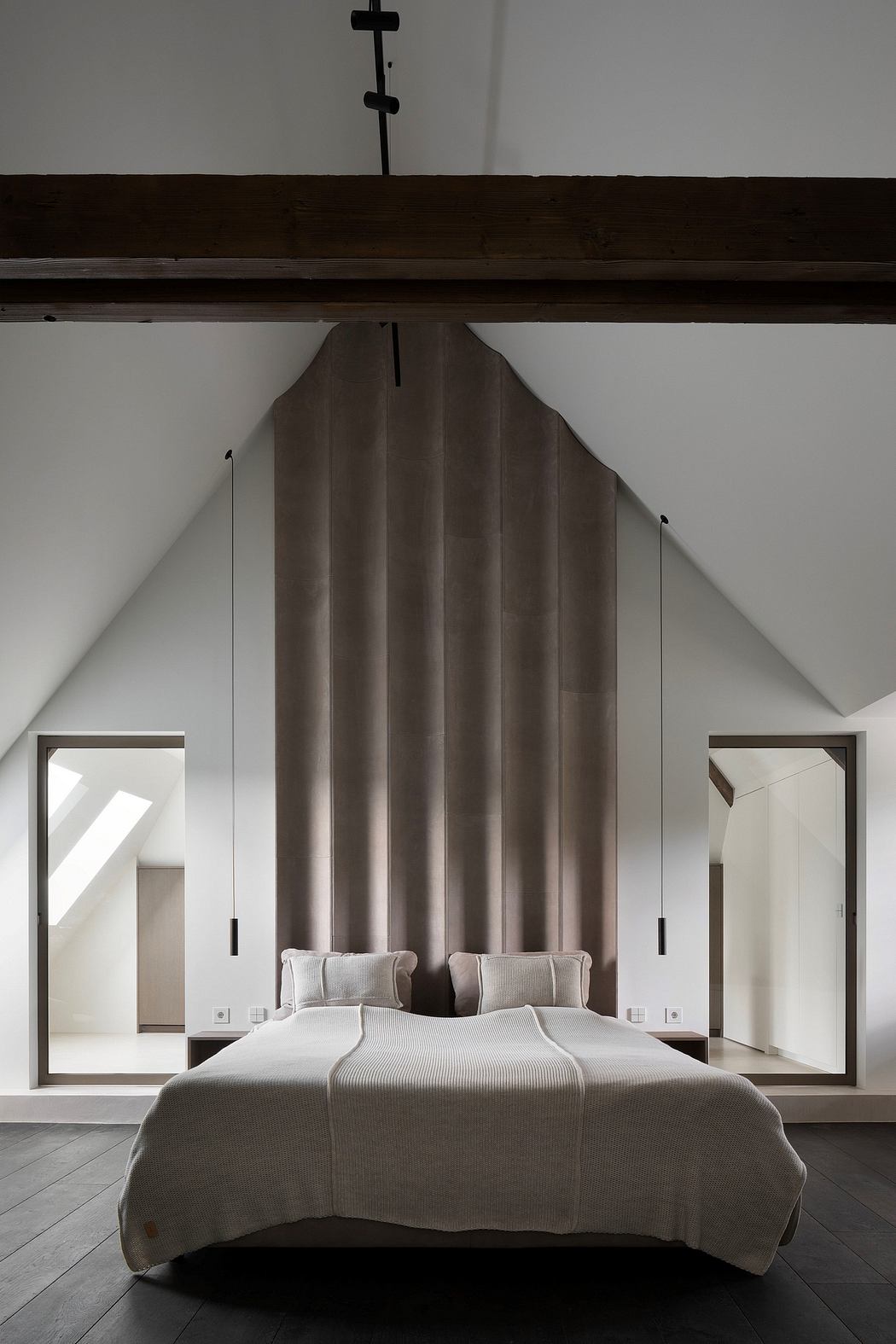 A modern bedroom with a large, pleated fabric headboard and minimalist design elements.