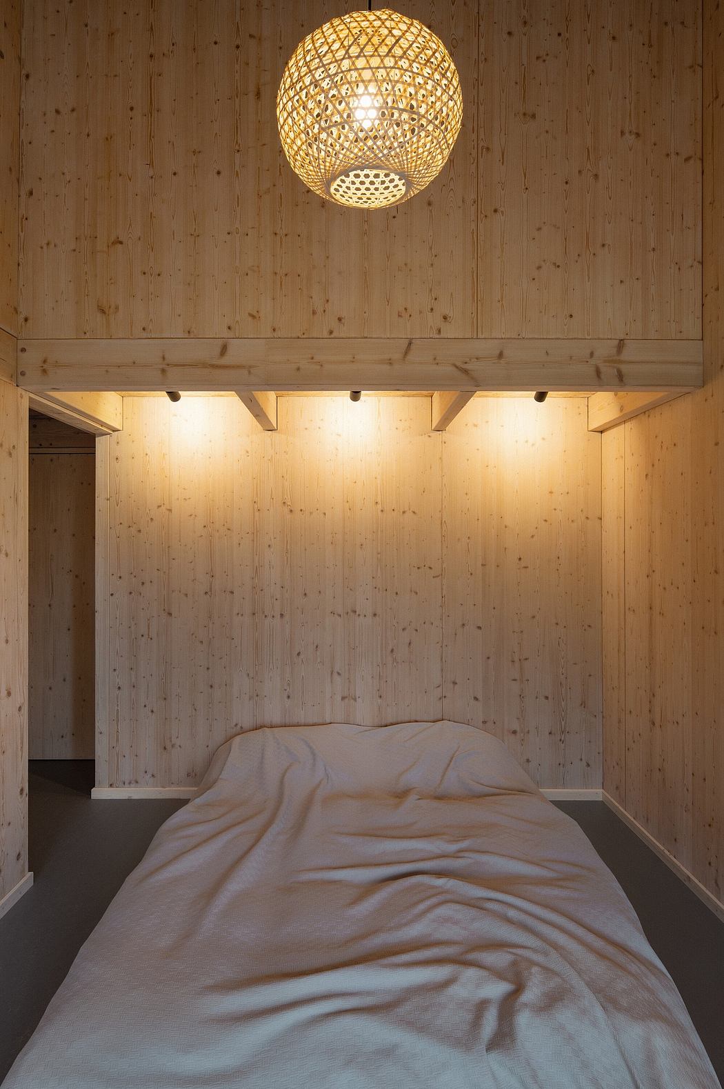 Cozy wooden bedroom with a unique woven light fixture and simple, minimalist decor.