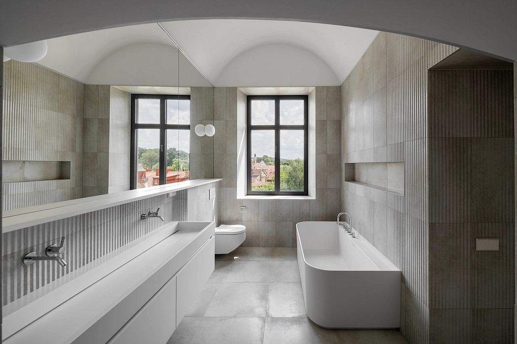 Spacious bathroom with arched ceilings, sleek vanity, and standalone bathtub with large windows.