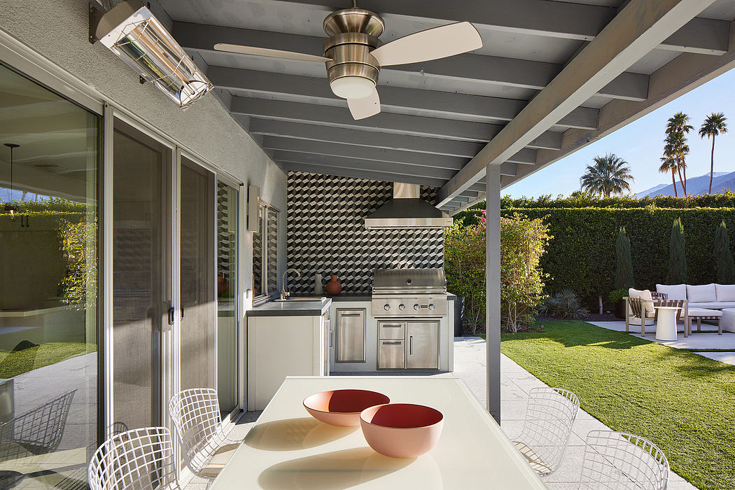 Covered outdoor kitchen with stainless steel appliances, metal beams, and seating area.