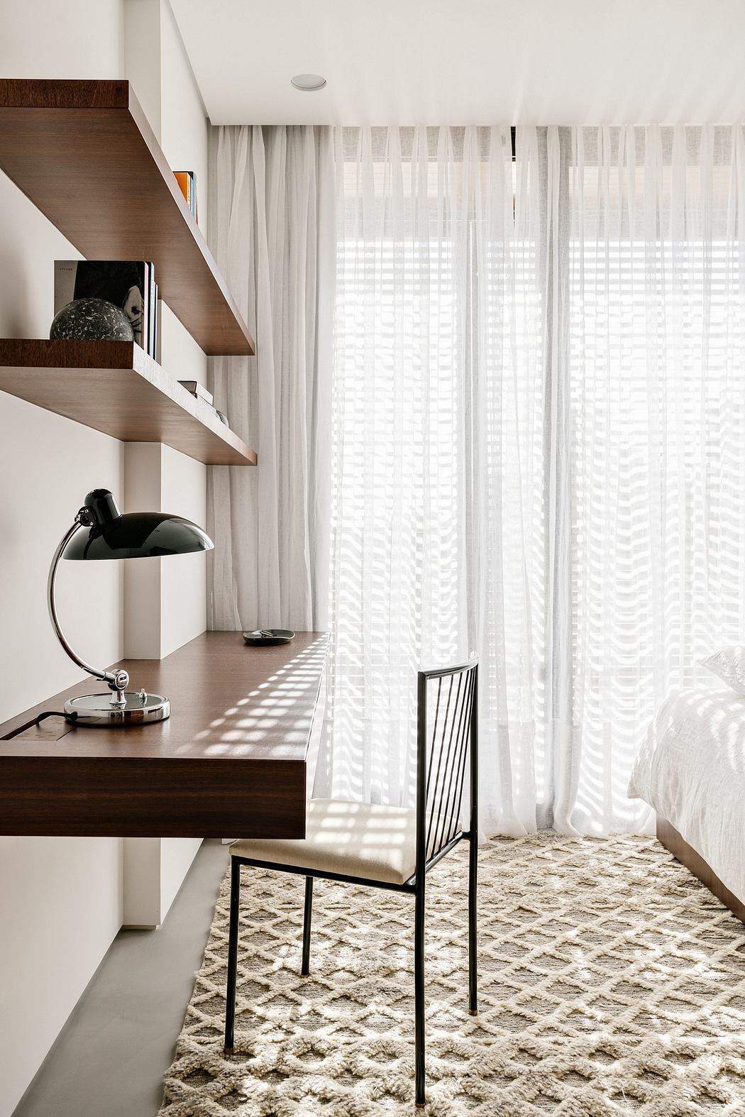 Modern bedroom with minimalist furniture, warm lighting, and a cozy textured rug.
