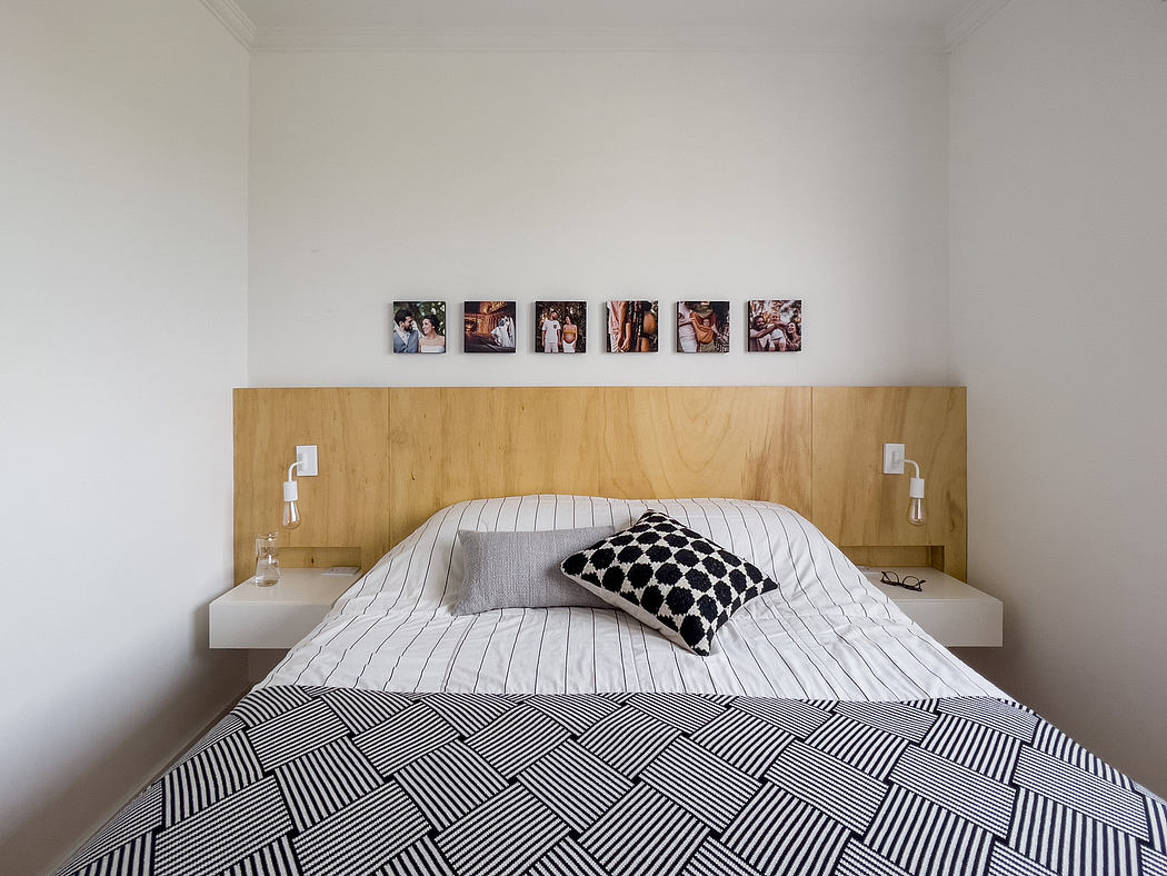 A modern bedroom with a wooden headboard and minimalist decor, featuring abstract art.