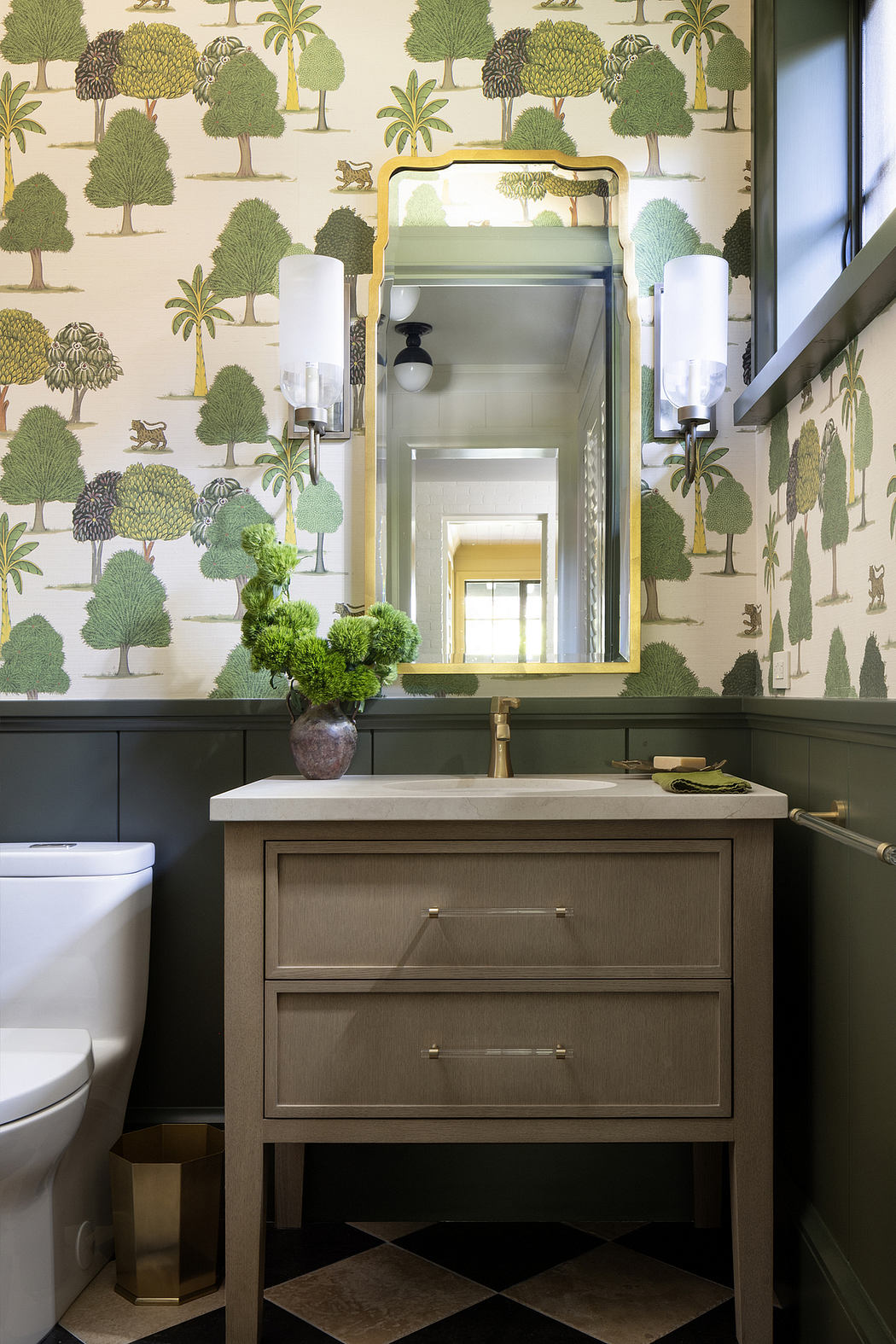 A whimsical bathroom with a tropical-themed wallpaper, a vanity with drawers, and a decorative mirror.