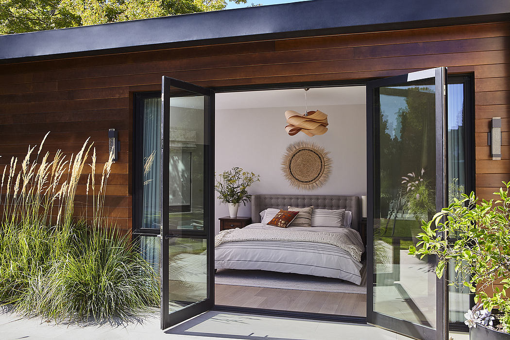 Sleek wooden exterior with floor-to-ceiling glass doors, leading to a cozy bedroom.