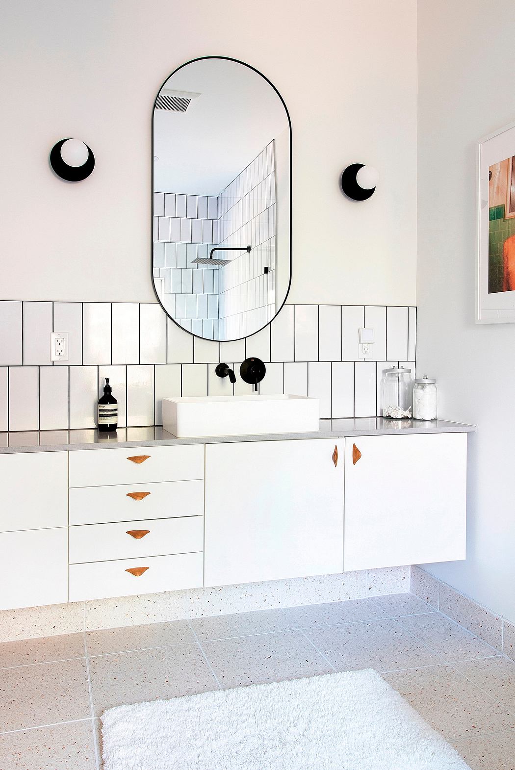 Minimalist bathroom design with arched mirror, tiled walls, and recessed lighting.