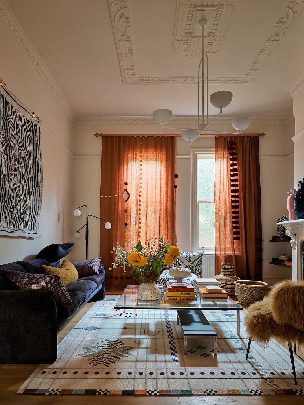 Ornate ceiling details, patterned rug, and eclectic furnishings create a cozy, artful space.