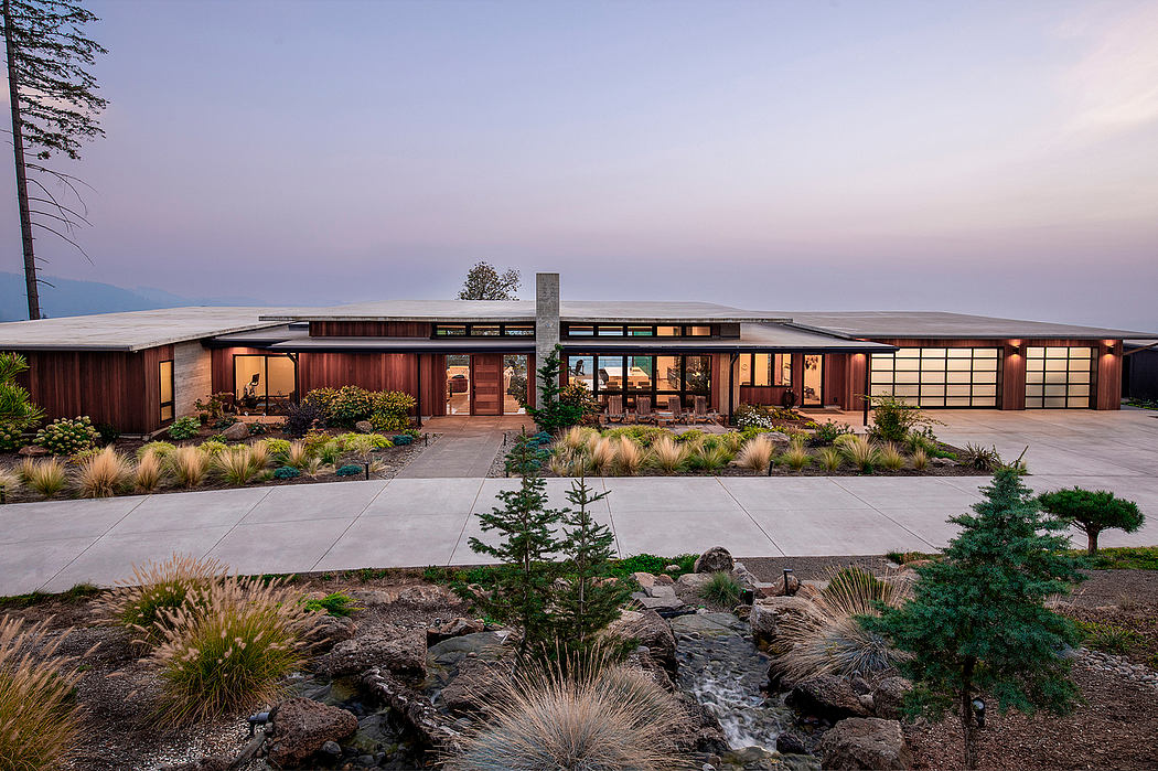 Sprawling modern home with wood paneling, water feature, and lush landscaping.